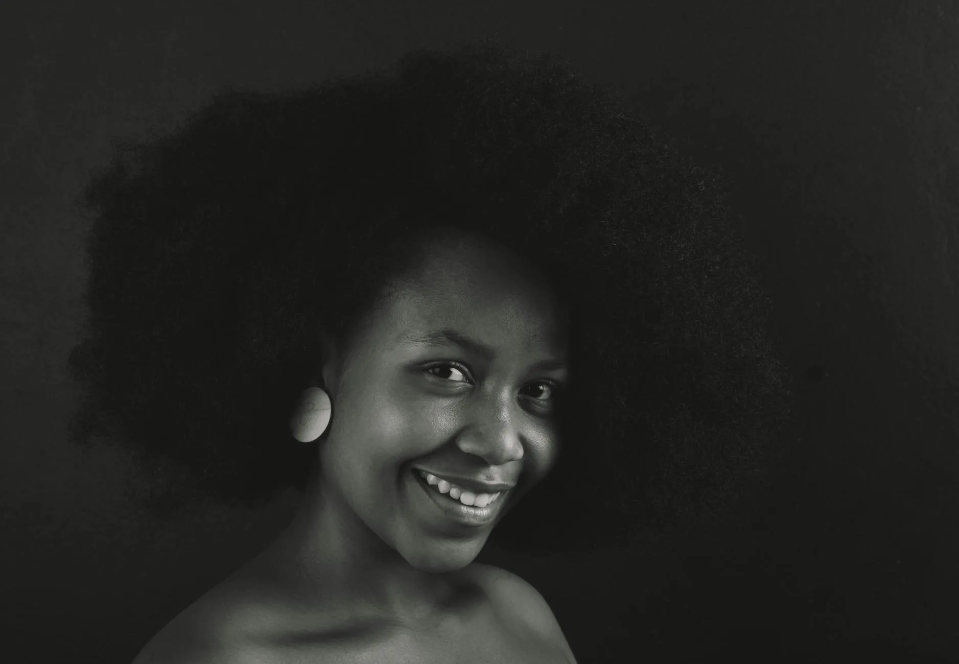 Monochrome close-up portrait of a smiling woman with afro hairstyle.