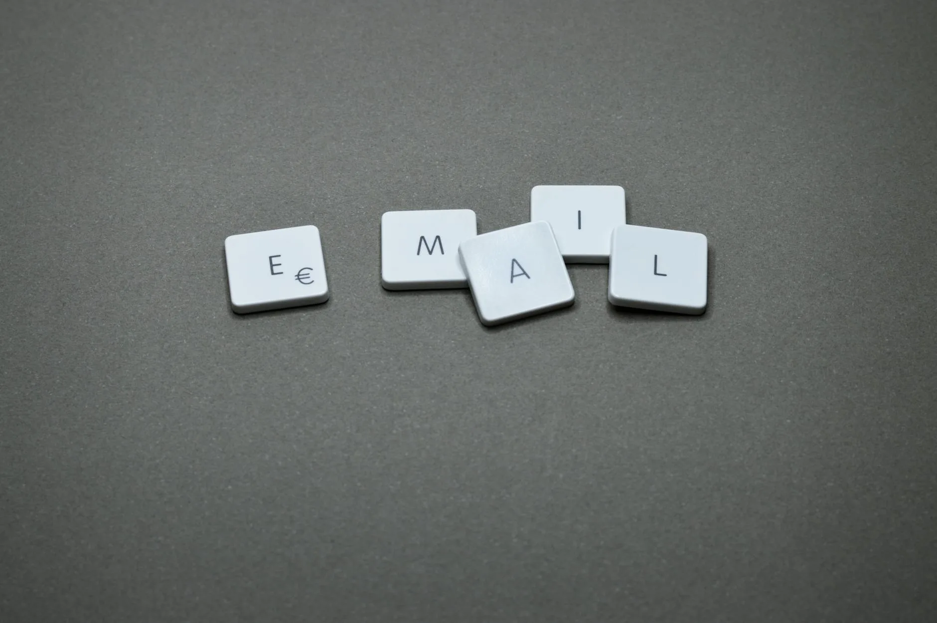 Close-up of the word 'email' formed with letter tiles on a gray surface.