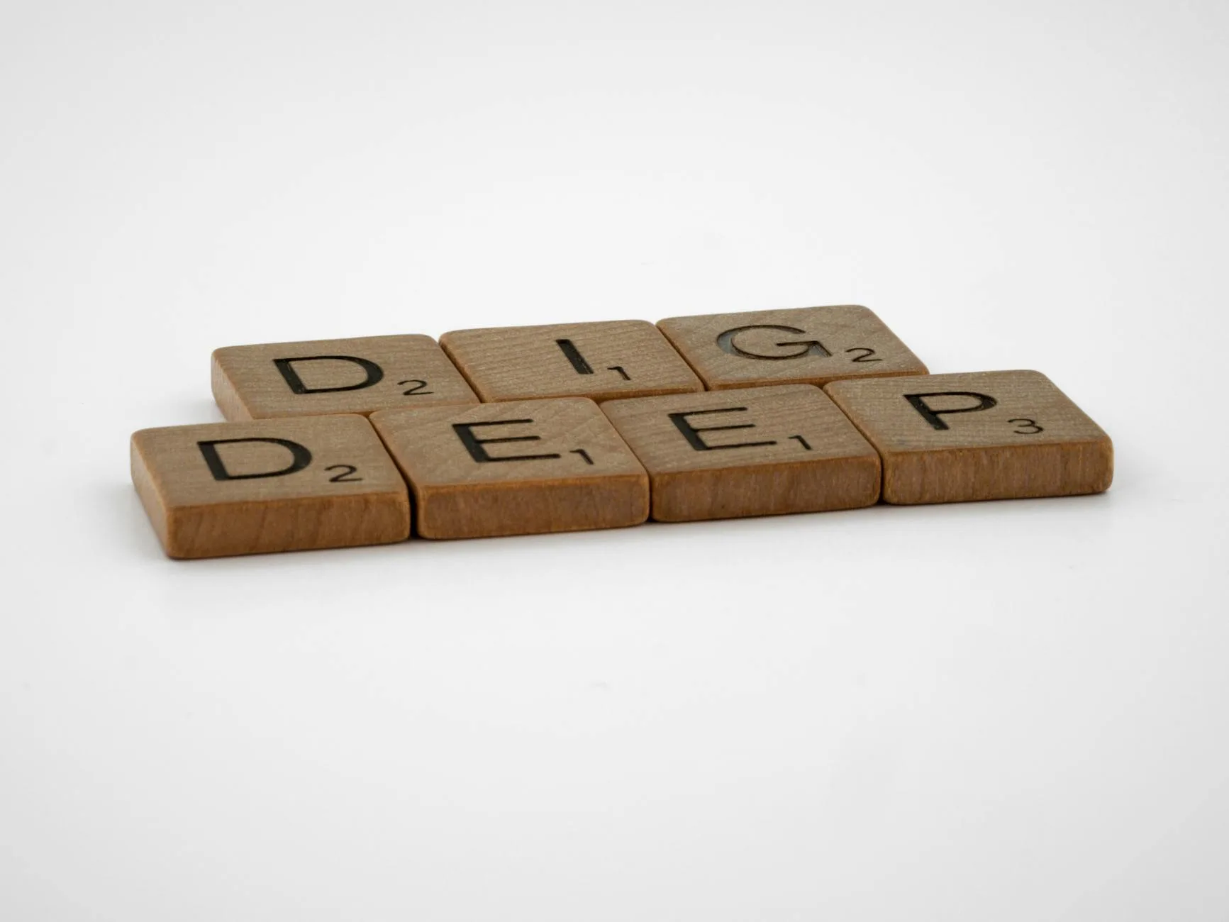 Scrabble tiles spelling 'Dig Deep' on a clean, white background. Perfect for conceptual and motivational themes.